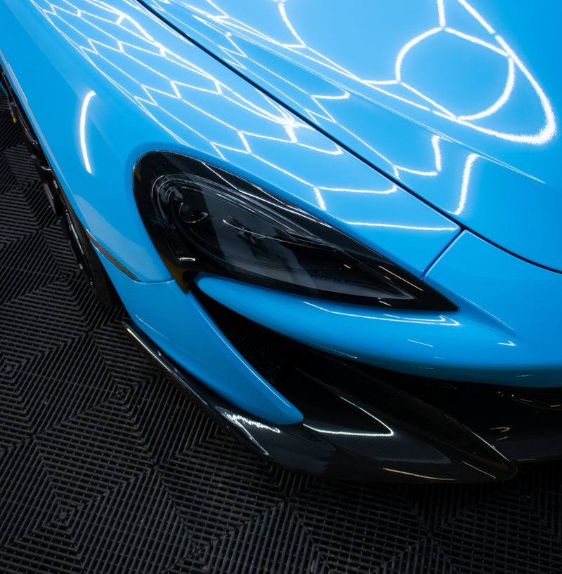 Mclaren 600lt wrapped in bright blue under a detailing bay hex lighting